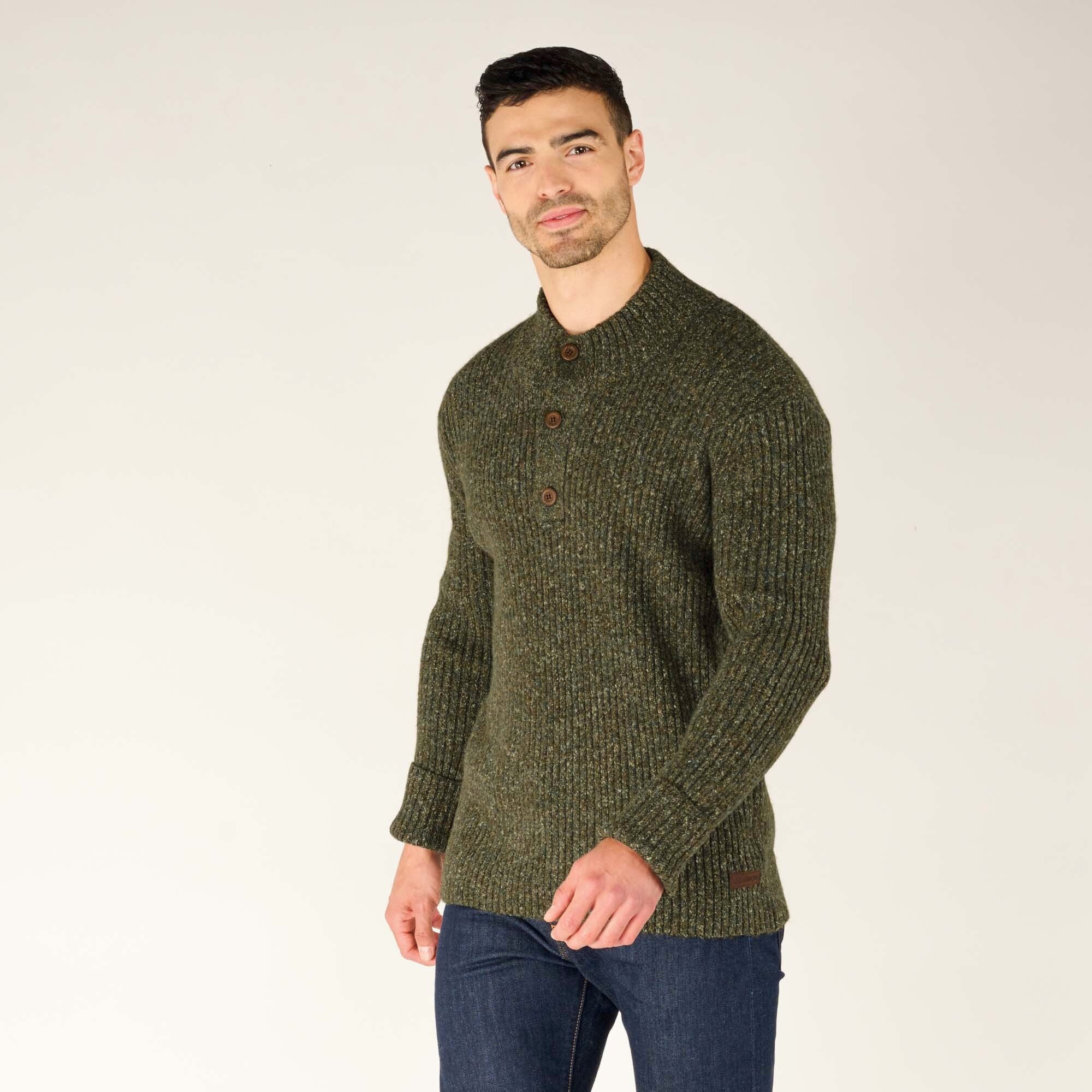 A three-quarter view of the man in the Sherpa Adventure Gear Ranga Button Mock Neck in Green, giving a closer look at the buttoned mock neck and the overall fit. He stands casually with a subtle smile.