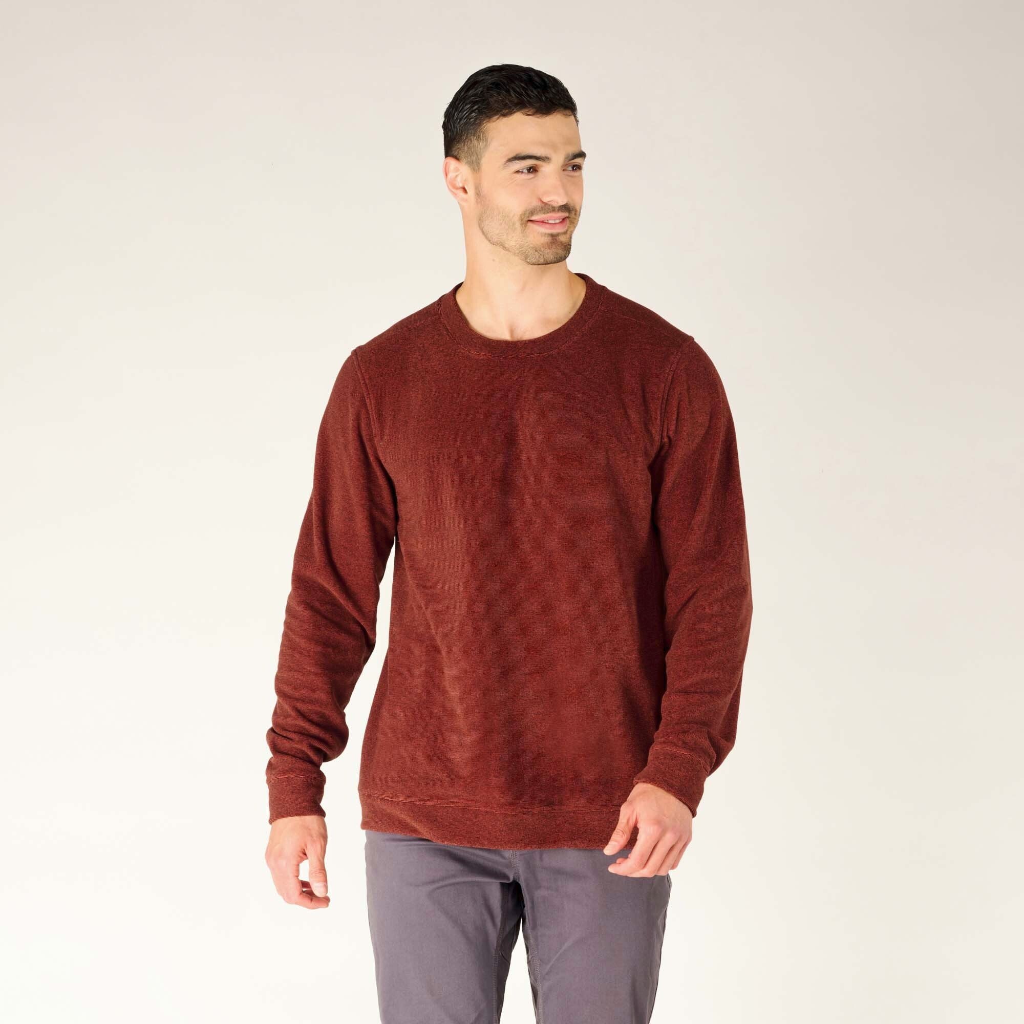 A side view captures the profile of the model wearing the Sherpa Adventure Gear Rolpa Crew in Red. This angle highlights the shoulder seam placement and the even drape of the fabric down the sides. The subtle texture of the fabric is more apparent, and the ribbed cuffs ensure the sleeves stay comfortably in place.