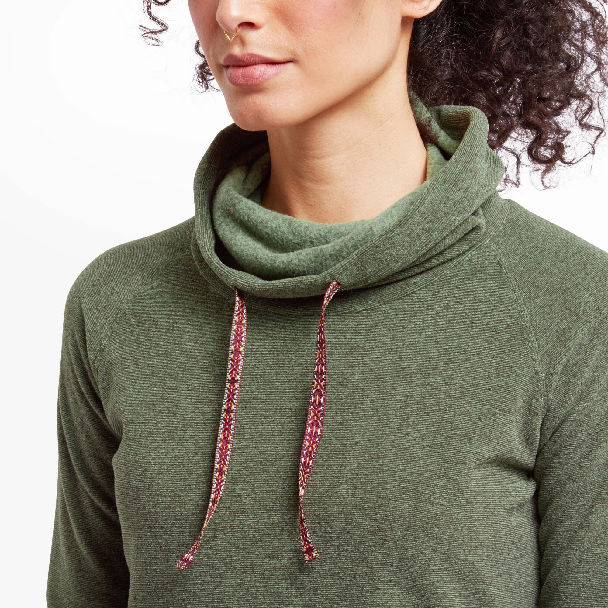 Close-up shot focusing on the cowl neck and drawstrings of the Sherpa Adventure Gear Rolpa Eco Pullover in Green. The drawstrings have an intricate red and white pattern, adding contrast to the green fabric. The soft texture of the fleece is visible, along with the gentle drape of the cowl.