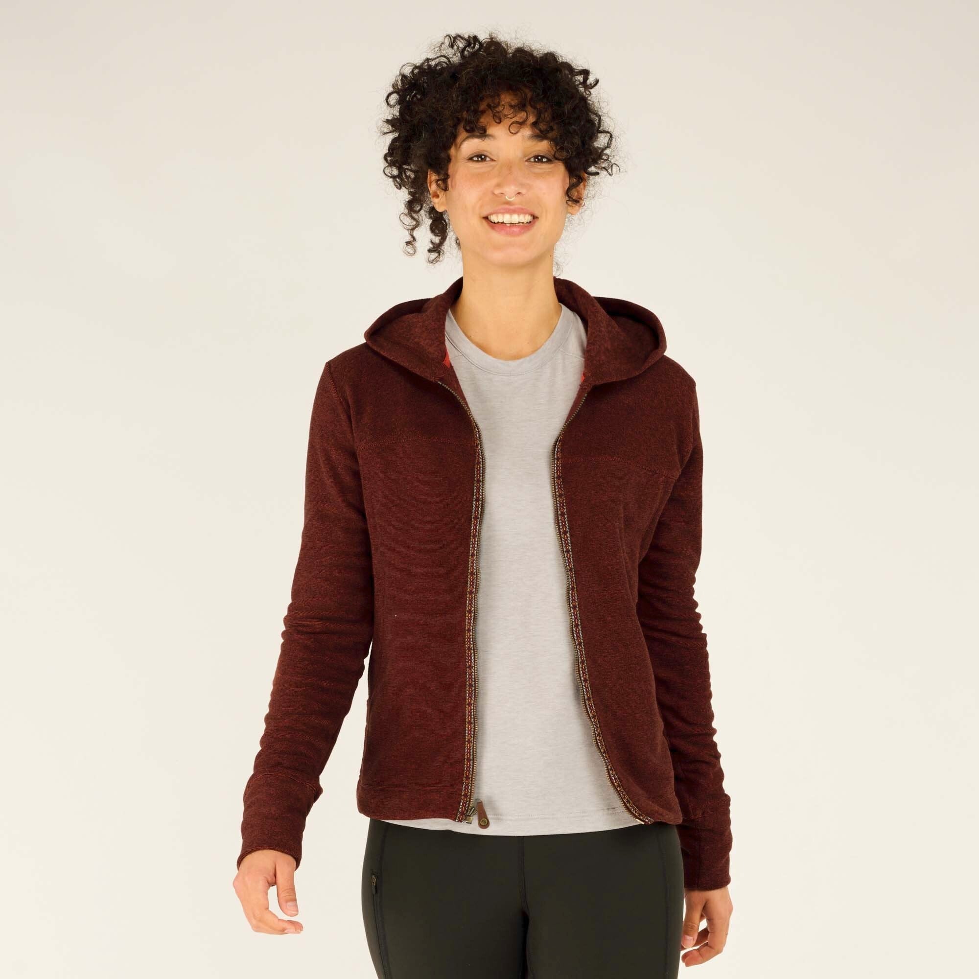 Back view of the Sherpa Adventure Gear Rolpa Full Zip Hoodie in Red. The hood lays flat against the model’s back, and the fleece fabric appears smooth. The stitching along the shoulders and down the center of the back is visible, adding subtle design elements. The hem extends evenly around the waist, showing the hoodie’s full coverage.