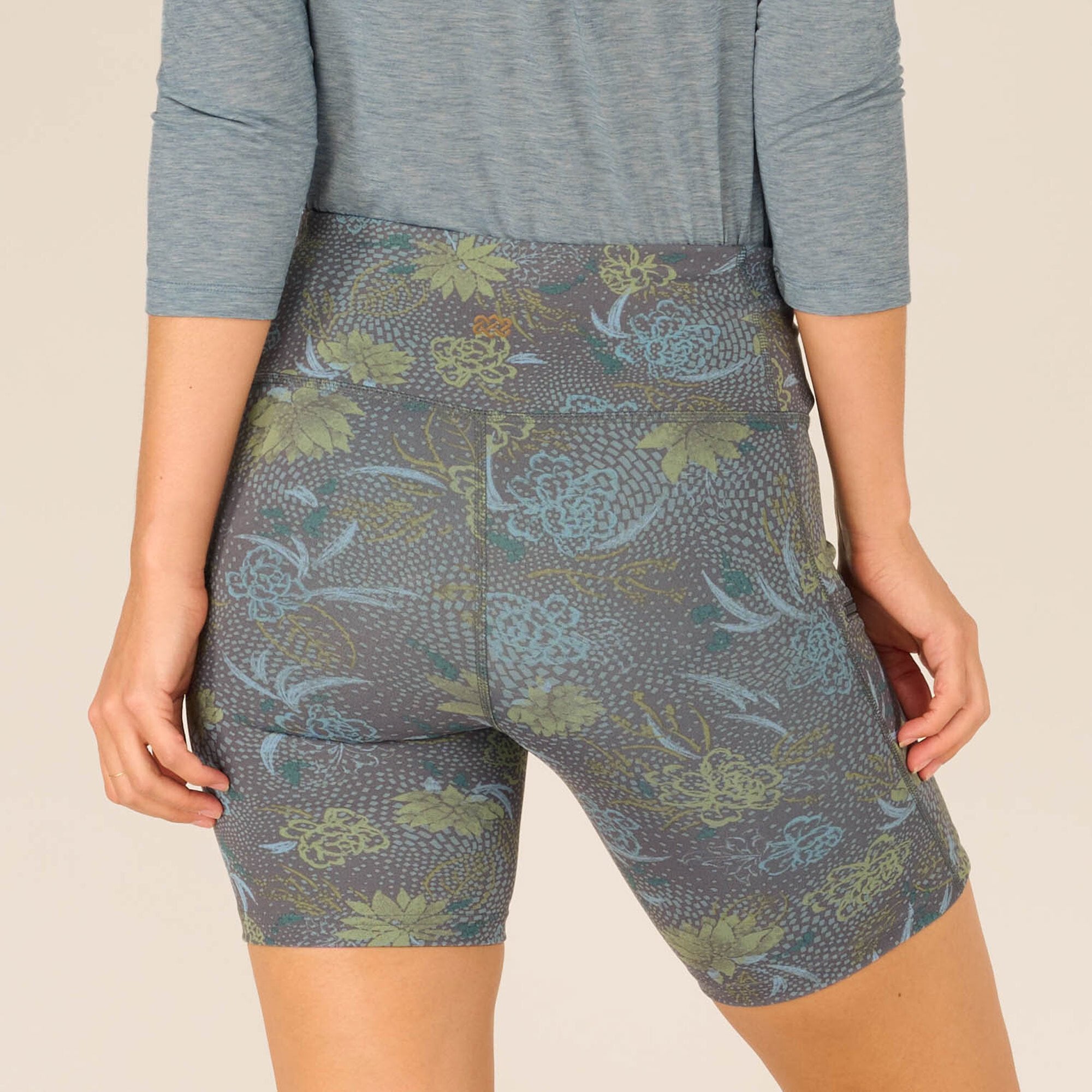 A focused view of the floral design and texture at the back of the Sherpa Adventure Gear Sahasa Shorts in Blue. The intricate combination of muted greens and blues against the grey fabric offers a closer look at the craftsmanship and aesthetic of the shorts.