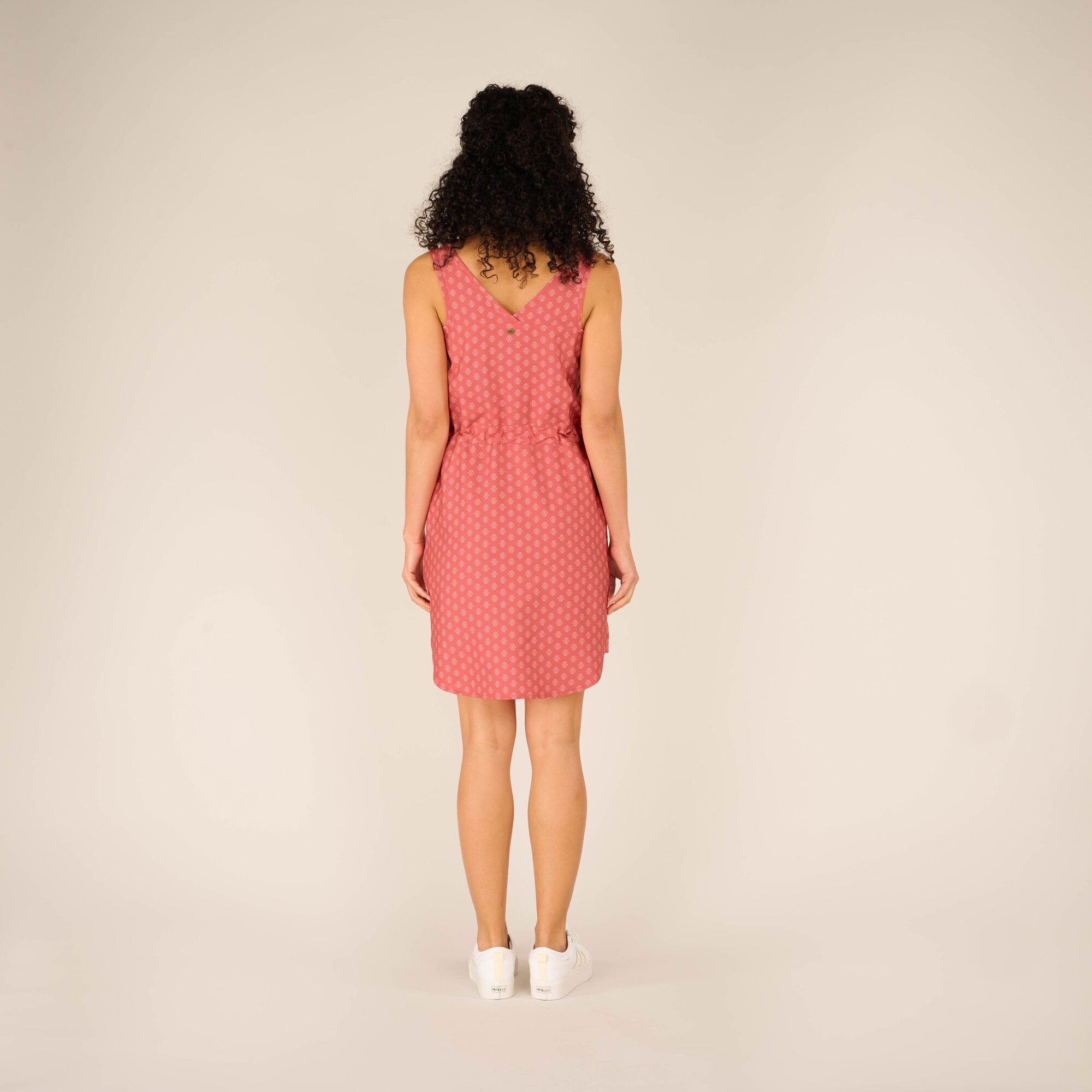 The back view of the Sherpa Adventure Gear Sajilo Dress in Pink, showcasing the V-shaped back neckline and a small decorative button detail. The straight hemline and the fit of the dress are clearly visible, emphasising its sleek and comfortable design.