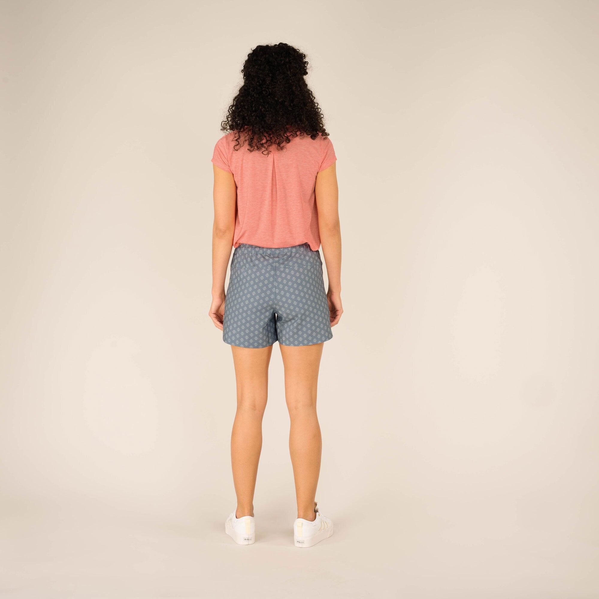 The back of the Sherpa Adventure Gear Sajilo Pull-On Shorts in Blue is showcased in this image, where the elastic waistband and overall fit are visible. The model stands facing away from the camera, providing a clear view of how the shorts fit around the waist and hips.