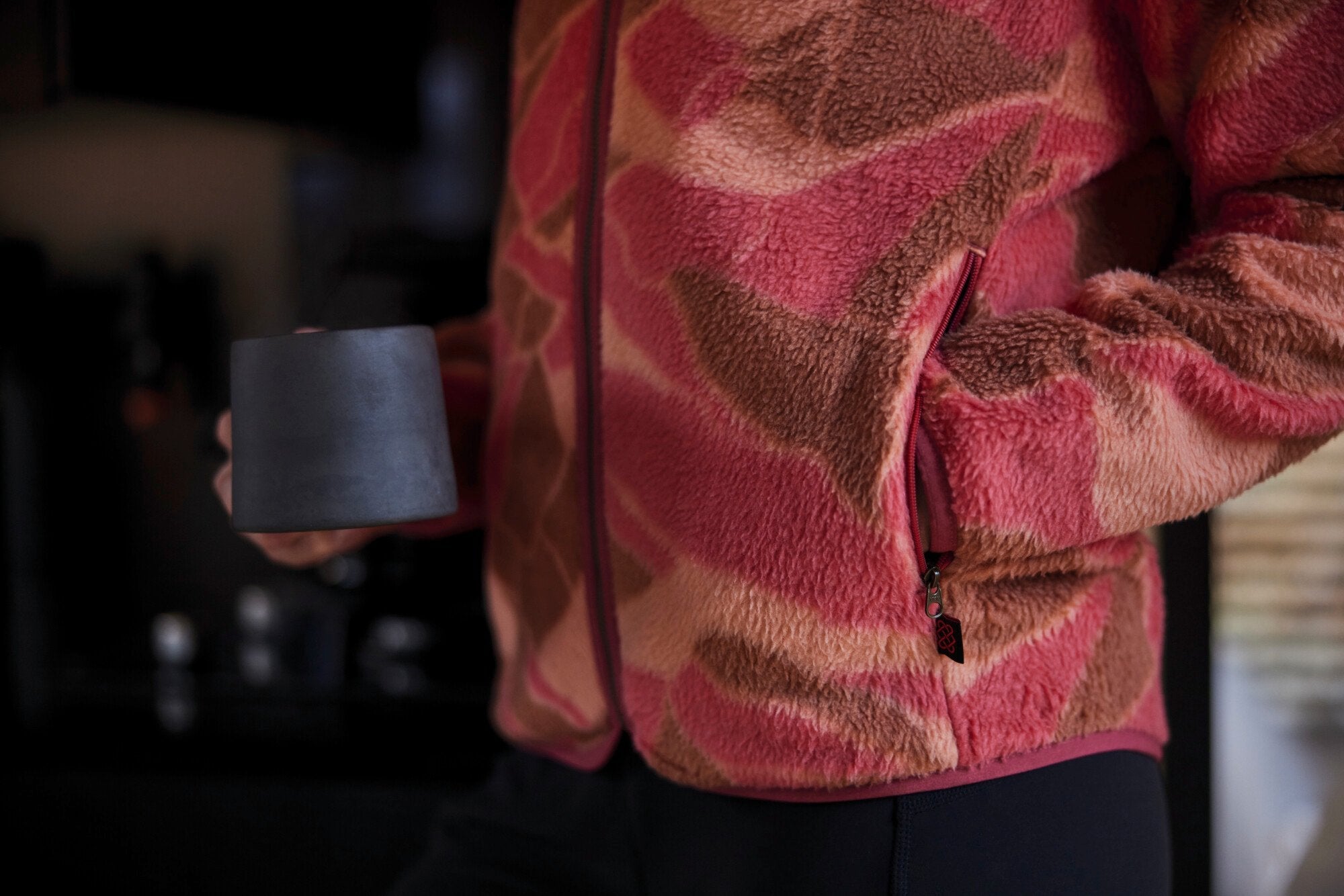 A close-up of the Sherpa Adventure Gear Uddesya Eco Quarter Zip in Red’s sleeve and cuff area. The fabric's fine texture and stitching details are highlighted. The cuff has a simple, clean finish without elastic or ribbing, ensuring comfort. The model’s wrist is slightly bent, demonstrating the flexibility of the fabric. The deep red color is rich and well-saturated, maintaining consistency with the rest of the garment.