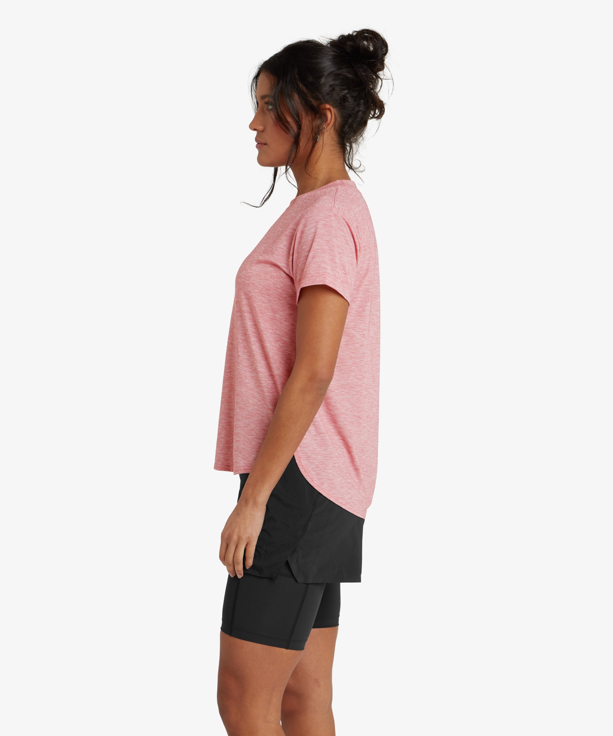 The back of the same Sherpa Adventure Gear Asha Crew in Red is shown, emphasising its seamless, clean look. The hemline is slightly rounded, and the woman's curly hair is styled in a ponytail, cascading down her back.