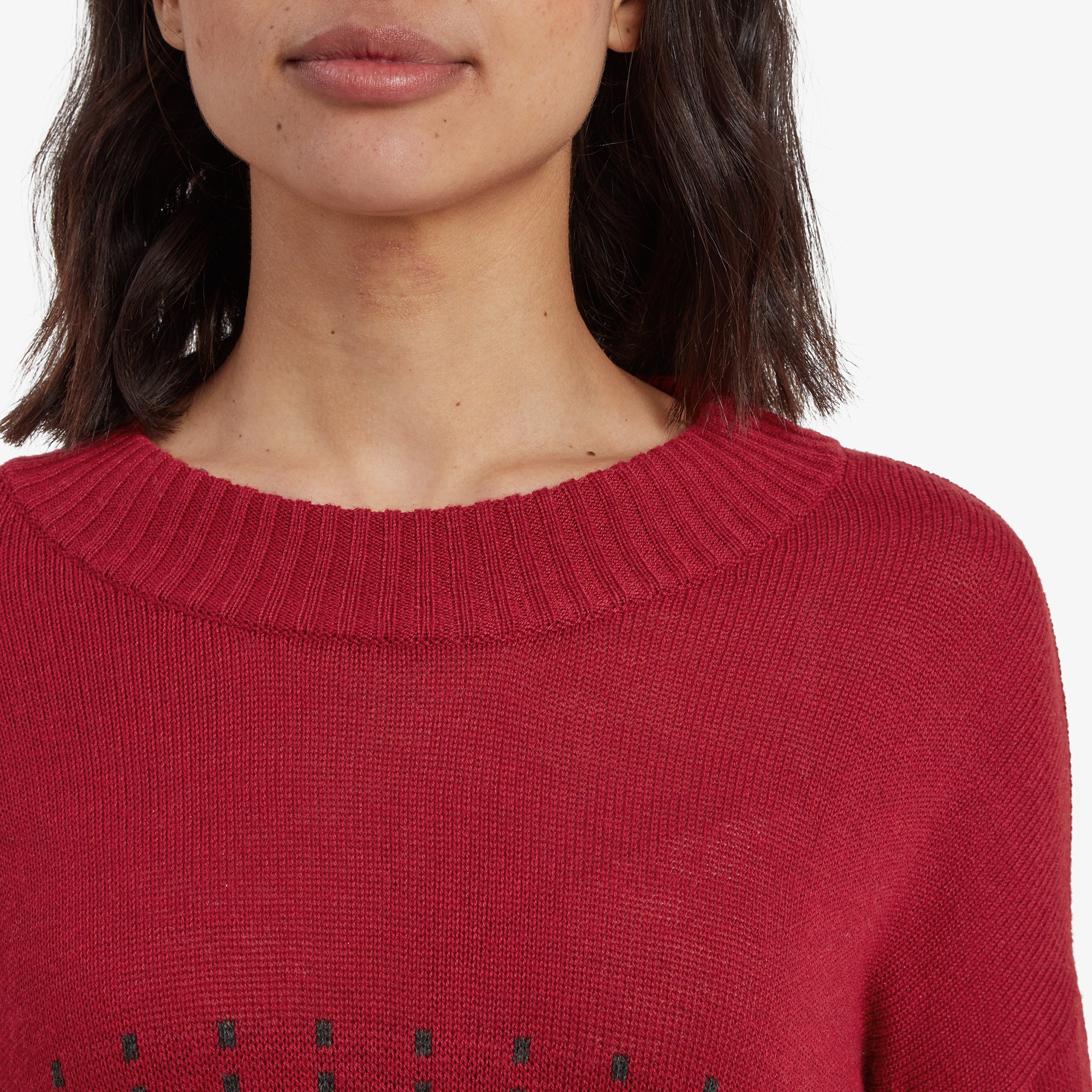 A close-up of the Sherpa Adventure Gear Devaki Eco Crew Sweater in Red's crew neckline. The fine knit texture is prominent, and the ribbed collar design adds detail to the overall look. The red color appears vibrant and rich in texture.