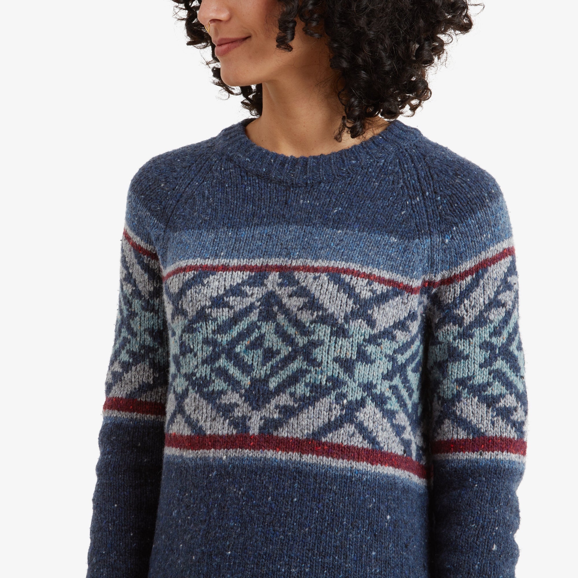 A close-up of the Sherpa Adventure Gear Dumji Long Sweater in Blue's pattern on the chest and upper sleeves. The intricate teal and white geometric shapes are accented with thin red lines, showcasing the craftsmanship and color contrast.