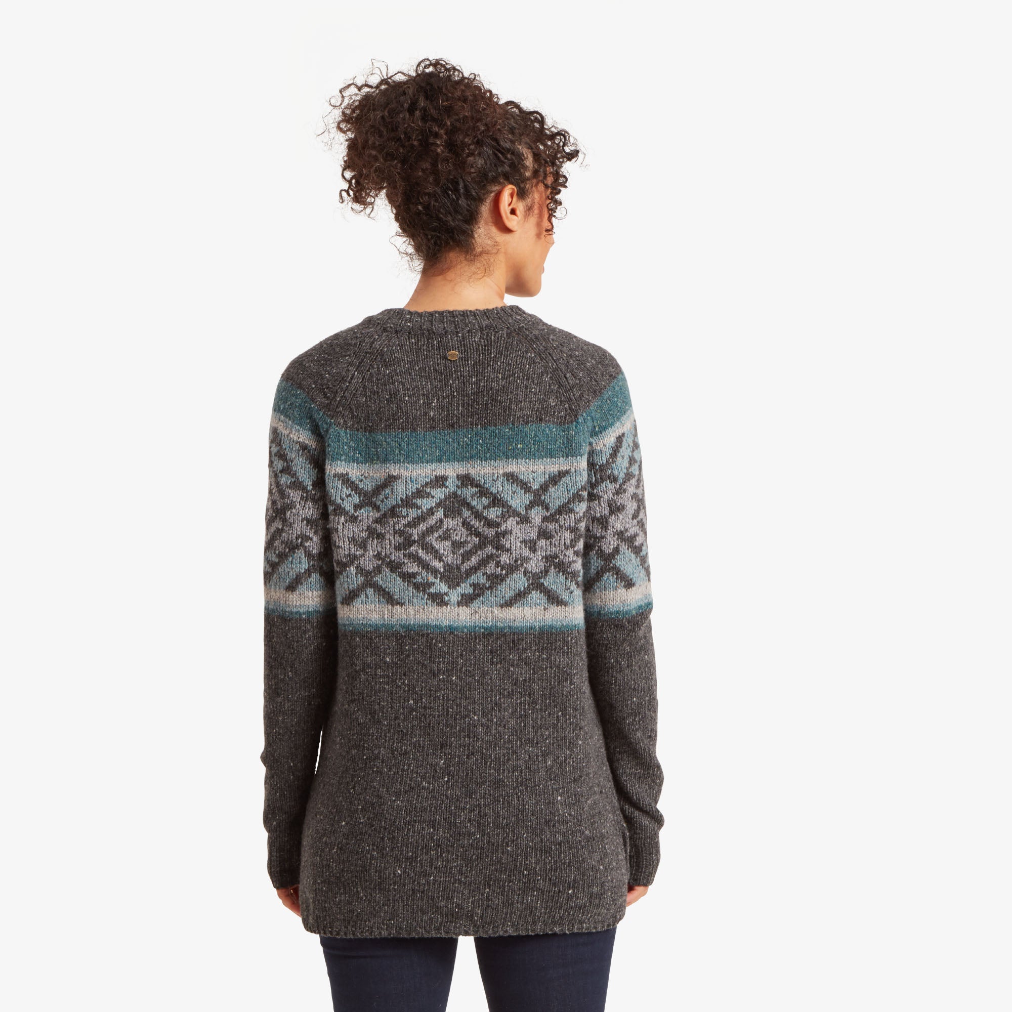 The back of the Sherpa Adventure Gear Dumji Long Sweater in Grey highlights its extended length and straight hemline, with a small brass logo detail on the upper back. The patterned yoke wraps around the back, maintaining the blue and grey geometric design.