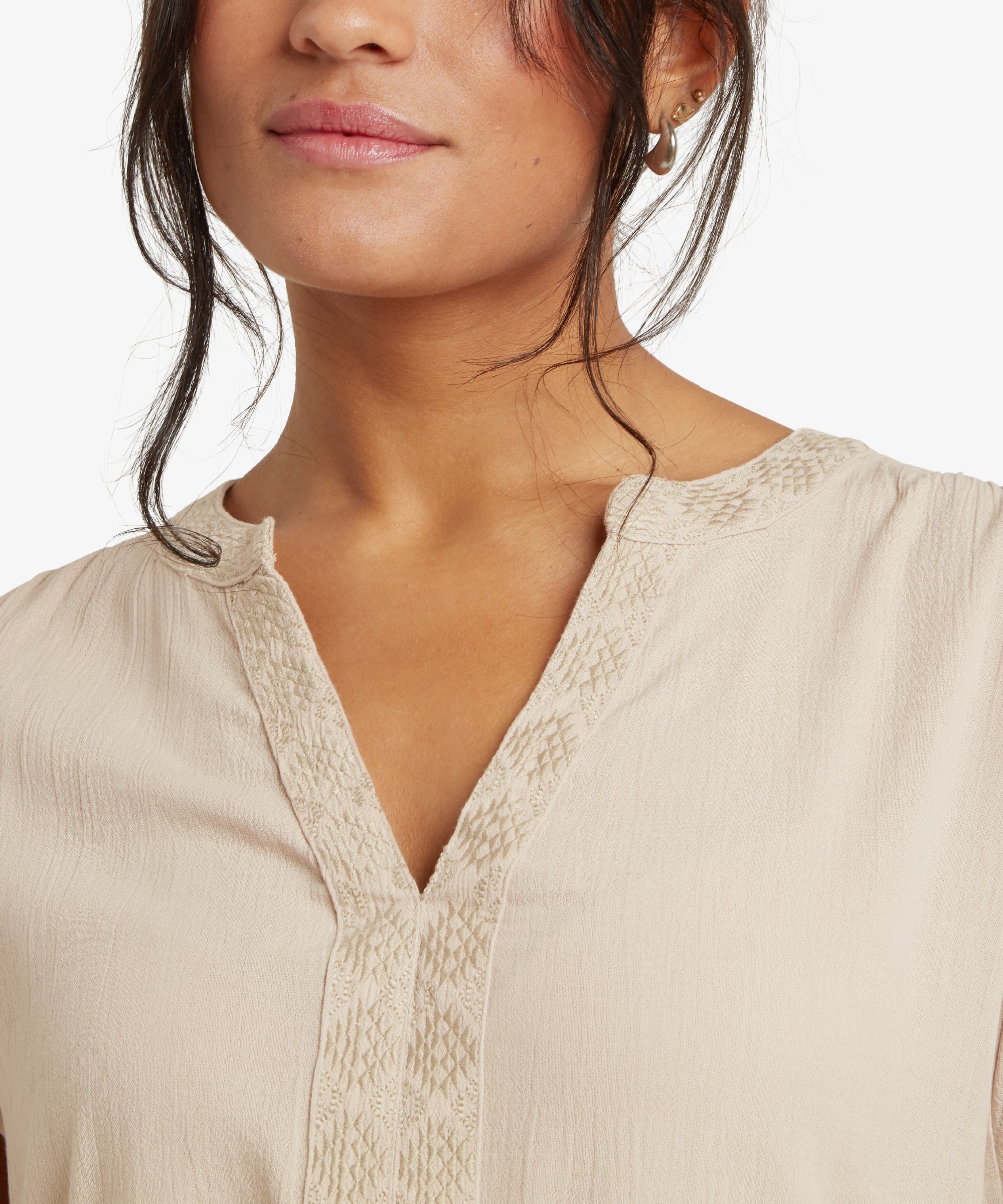 A detailed view of the back of the Sherpa Adventure Gear Hara Cap Sleeve Top in Beige. The soft gathers near the neckline are visible, along with the decorative button at the center. The embroidered trim along the neckline extends subtly toward the shoulders, adding texture and sophistication.