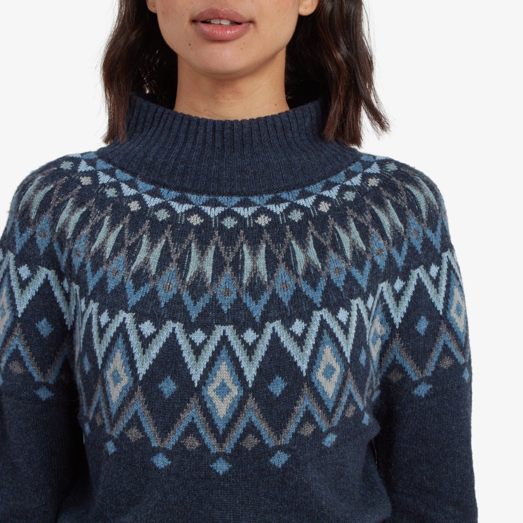 A close-up of the high, ribbed mock neck of the Sherpa Adventure Gear Indu Eco Mock Neck Sweater in Blue, drawing attention to the fine details of the Nordic pattern with diamond and zigzag motifs in shades of blue and white.