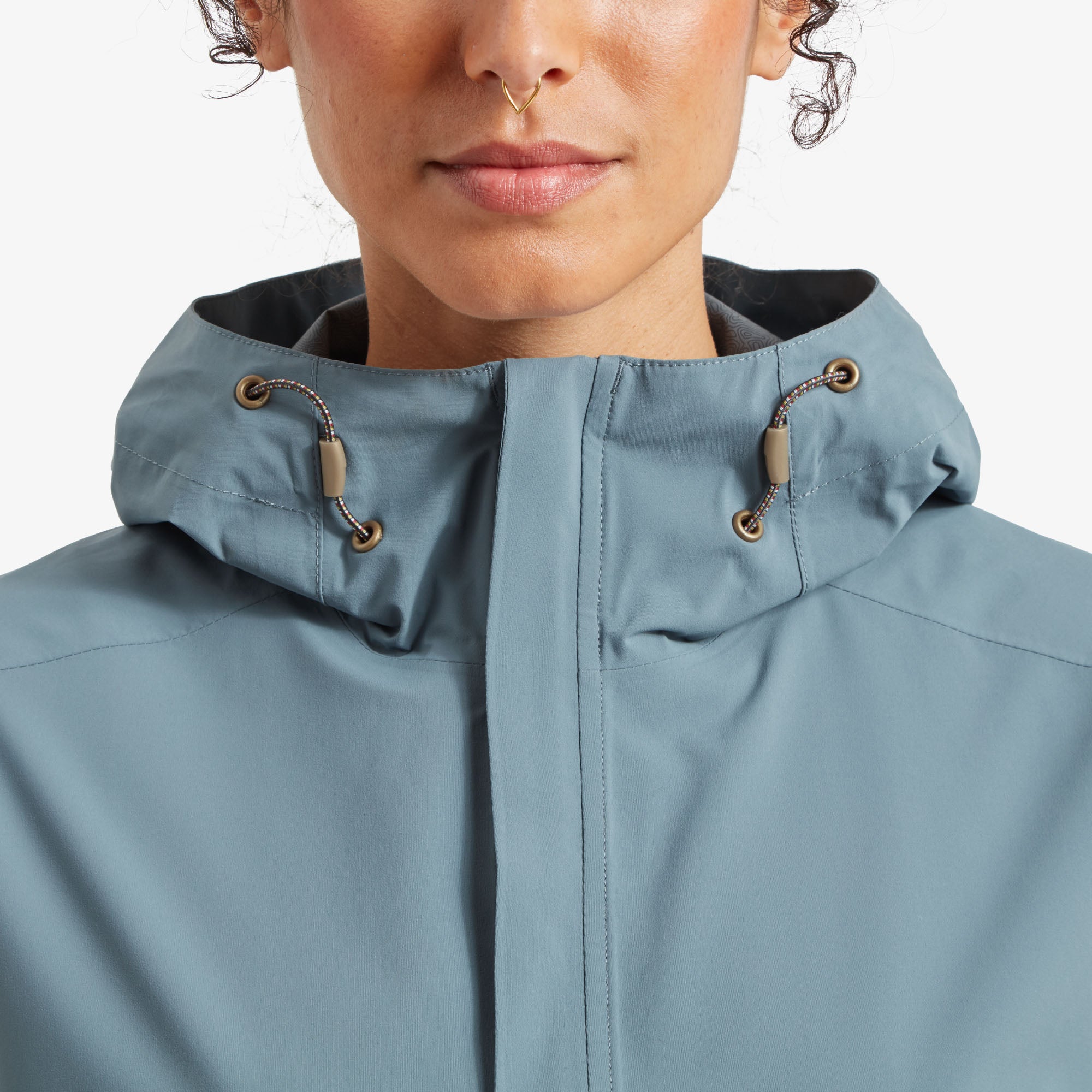 A zoomed-in view of the high neck and central zipper, showcasing fine details such as the water-resistant zipper and the securely fastened collar. The metal-tipped drawstrings and small grommets accentuate the Sherpa Adventure Gear Nima 2.5-Layer Jacket in Blue’s premium craftsmanship.