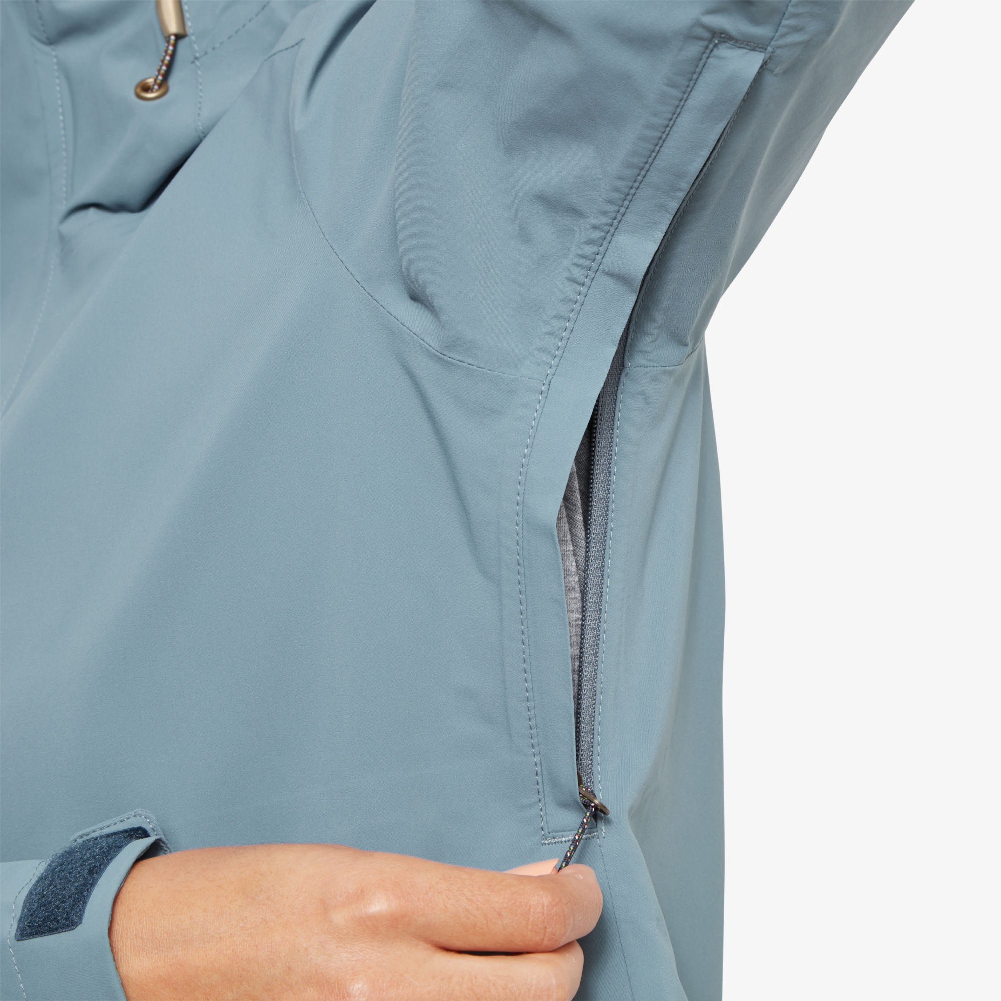 A close-up of the underarm area, revealing a hidden zippered vent for breathability. The zipper design allows for discreet airflow adjustments, maintaining the Sherpa Adventure Gear Nima 2.5-Layer Jacket in Blue's sleek look while enhancing comfort during active wear.