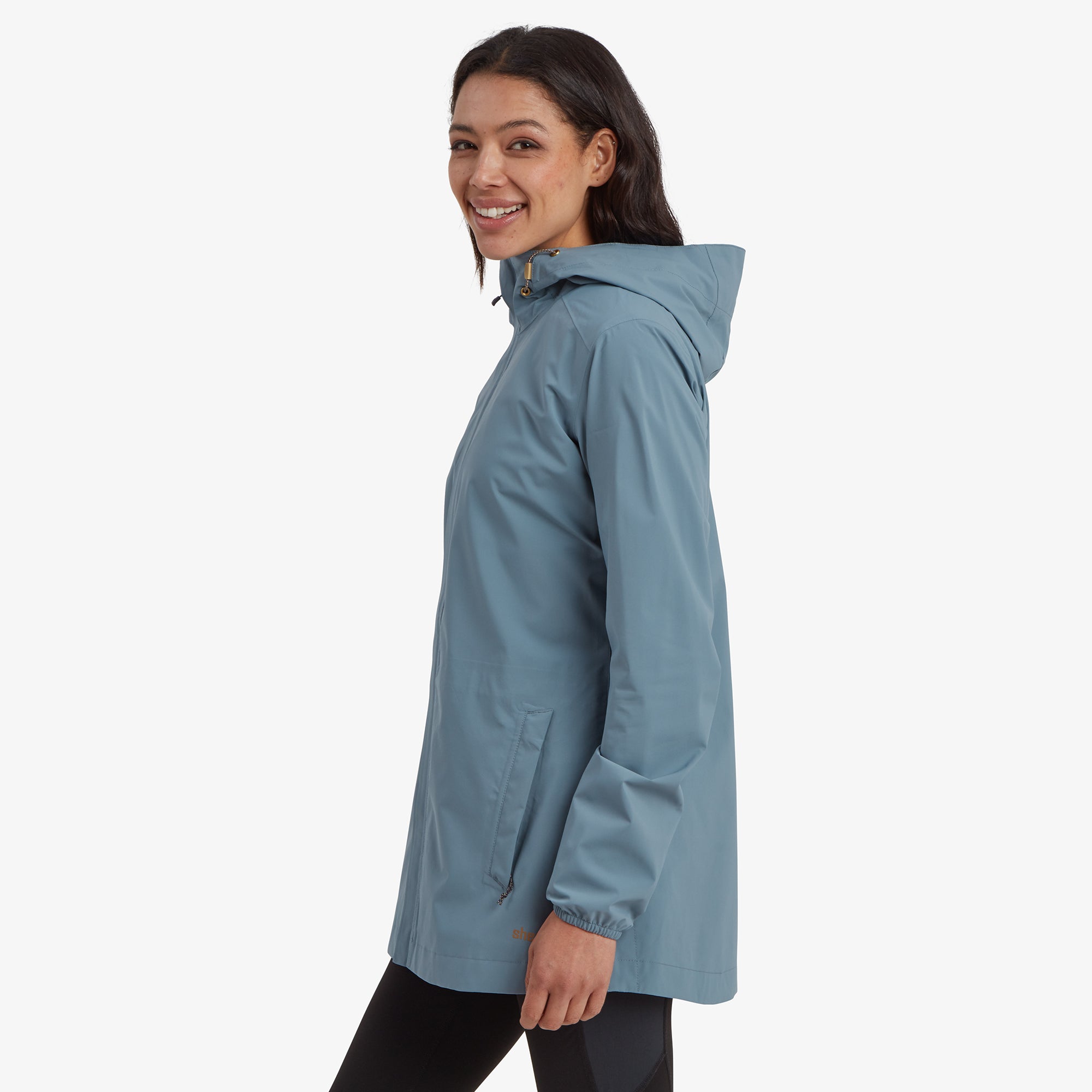 A side profile of the woman in the Sherpa Adventure Gear Nima 2.5-Layer Long Jacket in Blue, emphasising the hood and the jacket's tailored fit, which is both practical and stylish.