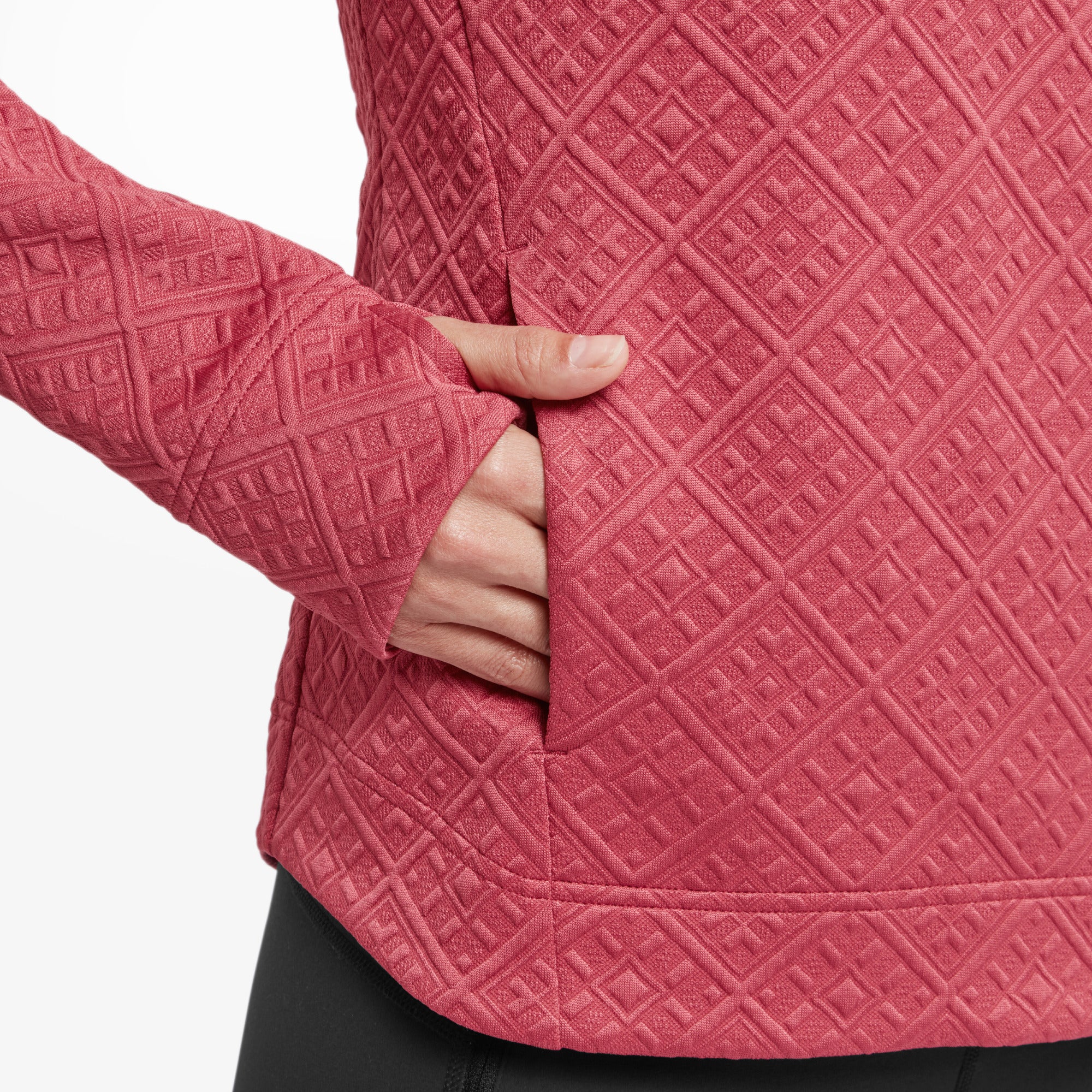 A close-up of the Sherpa Adventure Gear Nyano Pullover in Red's side pocket and sleeve. The intricate quilted pattern is prominently displayed, along with a functional pocket seamlessly integrated into the pullover's design. The sleeve includes thumbholes, highlighting its thoughtful and practical features.