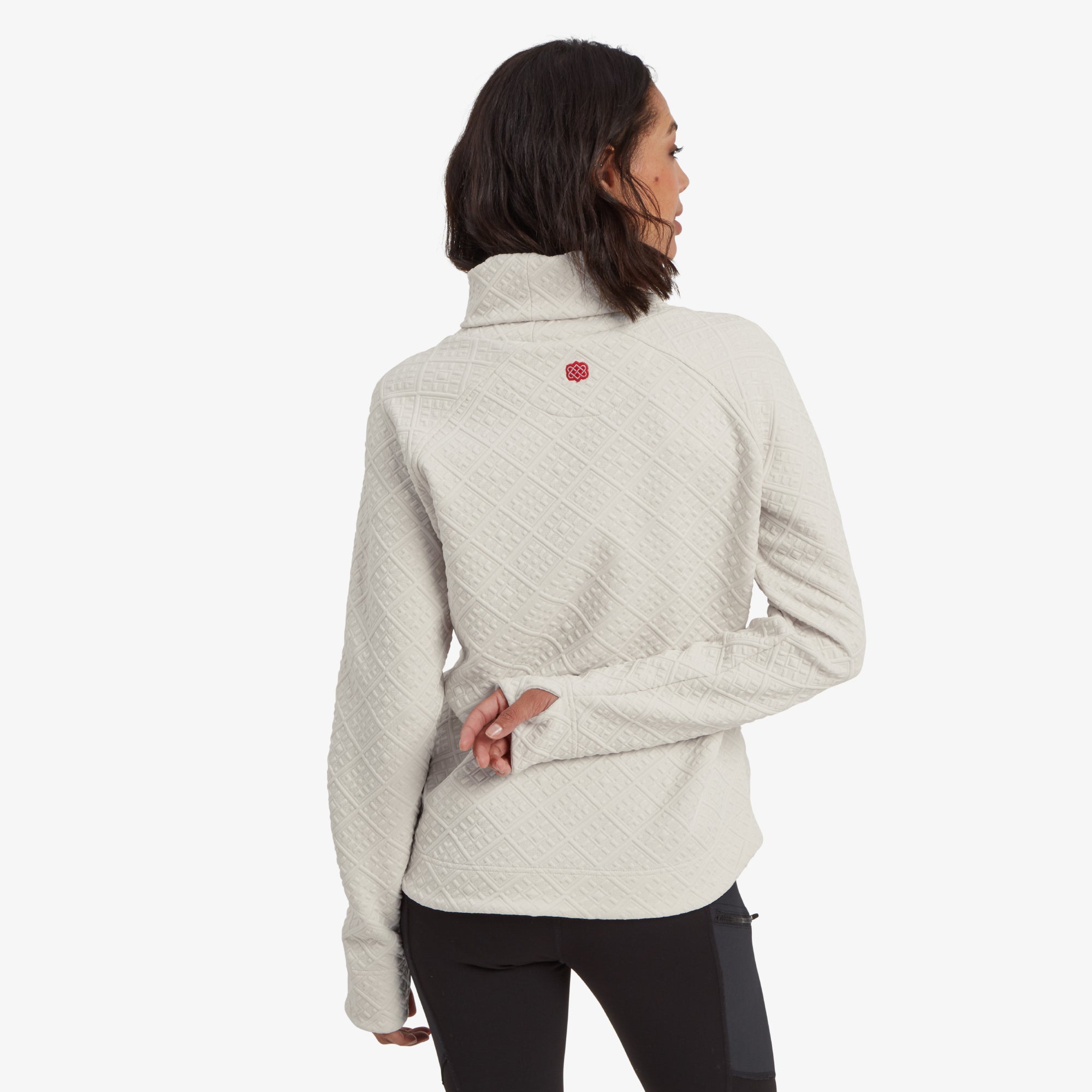 A rear view of the Sherpa Adventure Gear Nyano Pullover in White, featuring the intricate diamond quilting pattern extending to the back. The Sherpa Adventure Gear red logo detail is subtly embroidered at the upper back, adding a pop of contrast to the cream fabric. The relaxed fit provides a flattering silhouette.