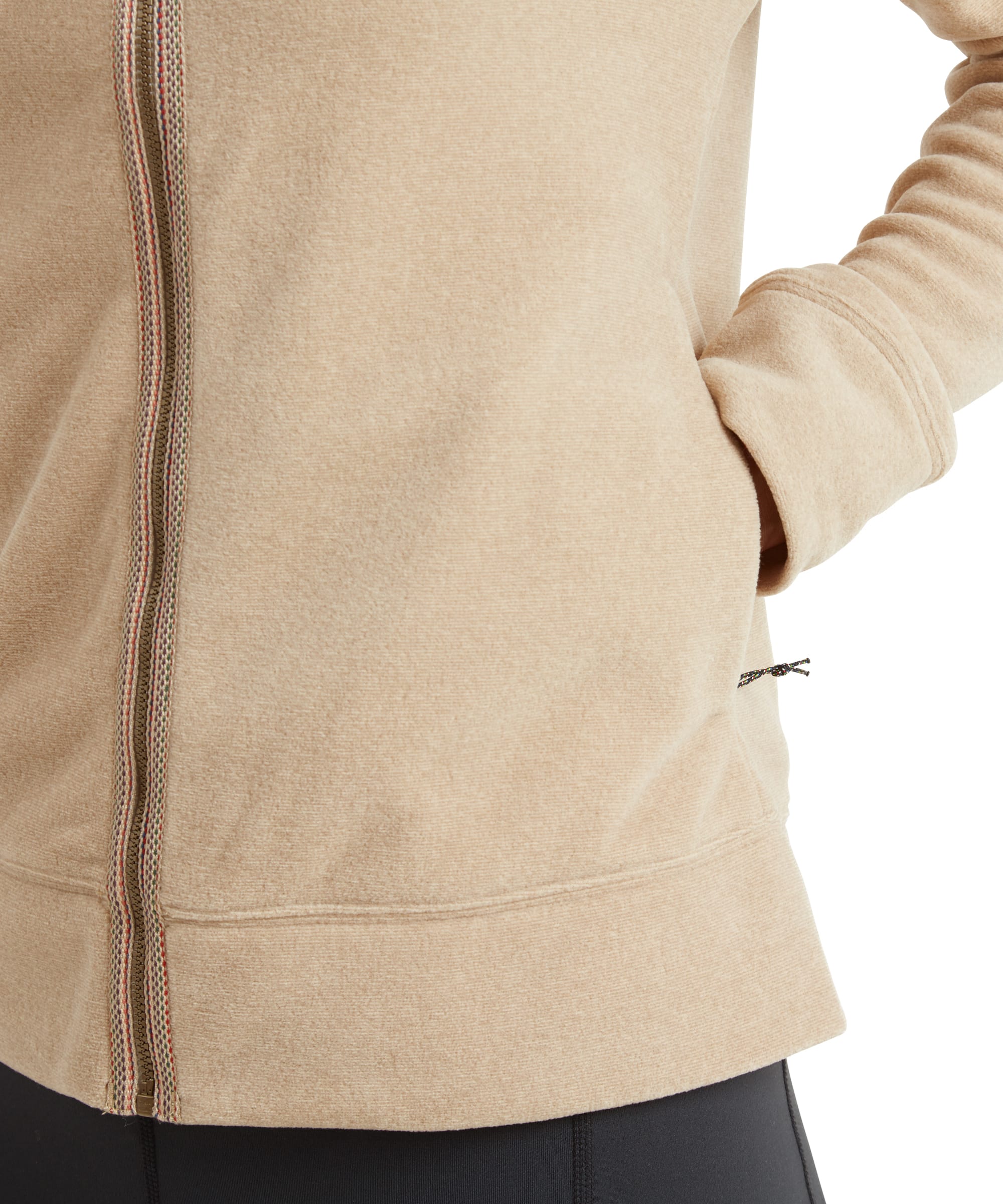 A close-up of the Sherpa Adventure Gear Rolpa Eco Jacket in Beige, capturing the brown trim binding around the zip. The zip pull can be clearly seem in a leatherette fabric with an embossed Sherpa logo on the end.