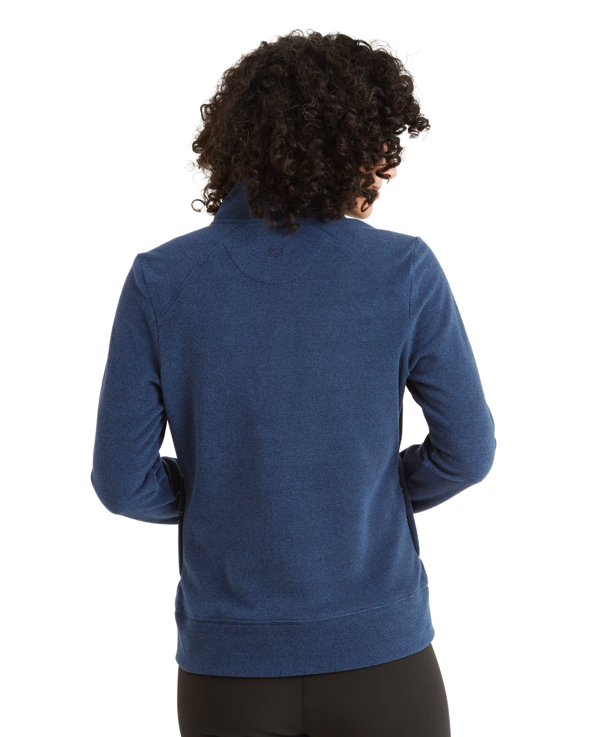 A back view of the Sherpa Adventure Gear Rolpa Eco Jacket in Blue, showing the high collar and subtle stitched detailing on the upper back. The jacket has a slightly curved hem. The model’s dark curly hair is visible from behind.