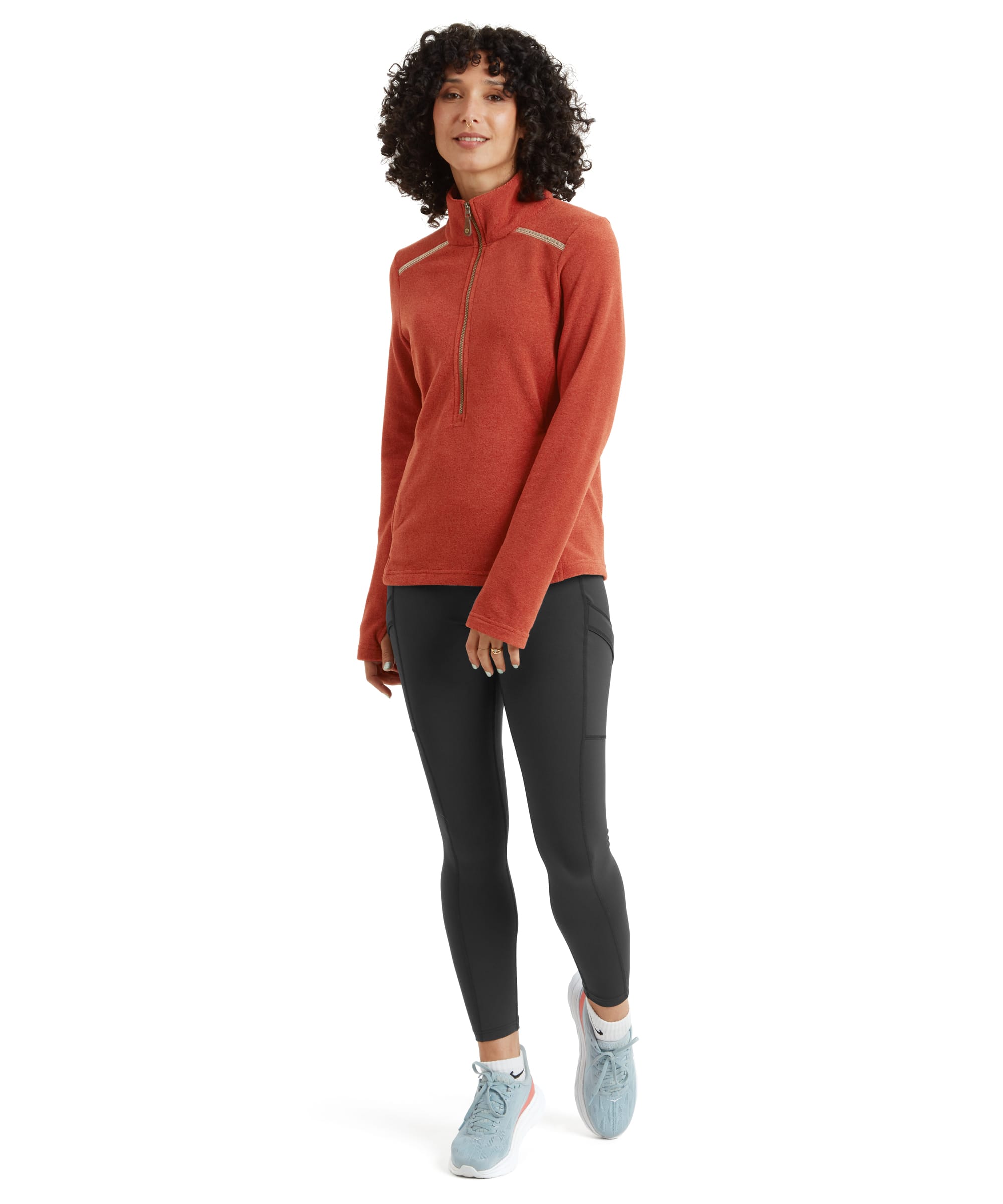 A back view showcasing the Sherpa Adventure Gear Rolpa Eco Pullover Zip in Brown's clean and minimalist design. The shoulder seams feature contrast stitching for added detail, and the fabric has a subtle texture. The hemline sits slightly below the hips, and the model's curly hair frames the outfit.