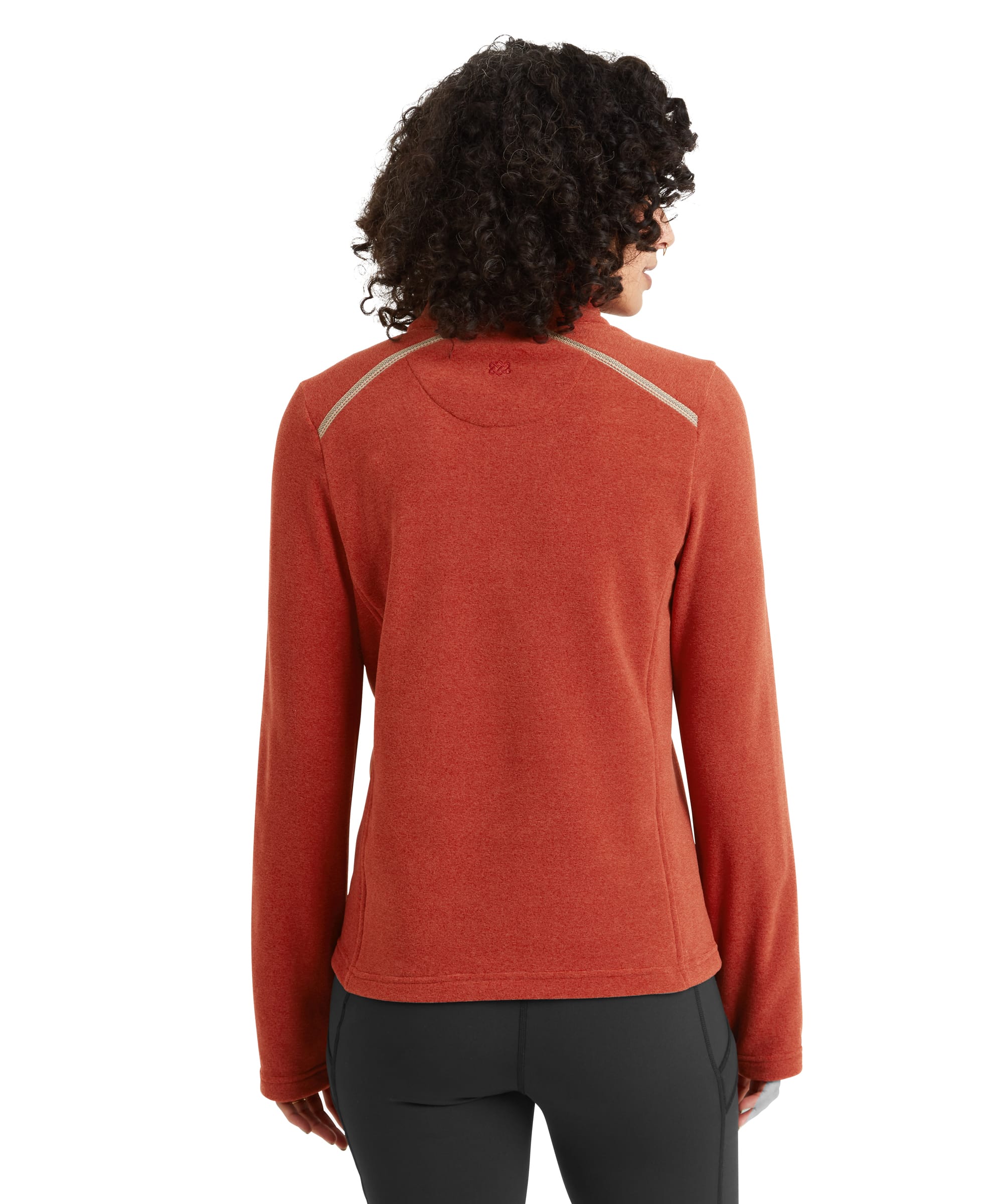 A close-up view of the Sherpa Adventure Gear Rolpa Eco Pullover Zip in Brown's side pocket, emphasising its practicality and cozy design. The model's hand rests inside the pocket, highlighting the garment's textured fabric and ergonomic seam placement. The pullover is paired with black leggings for a sleek aesthetic.