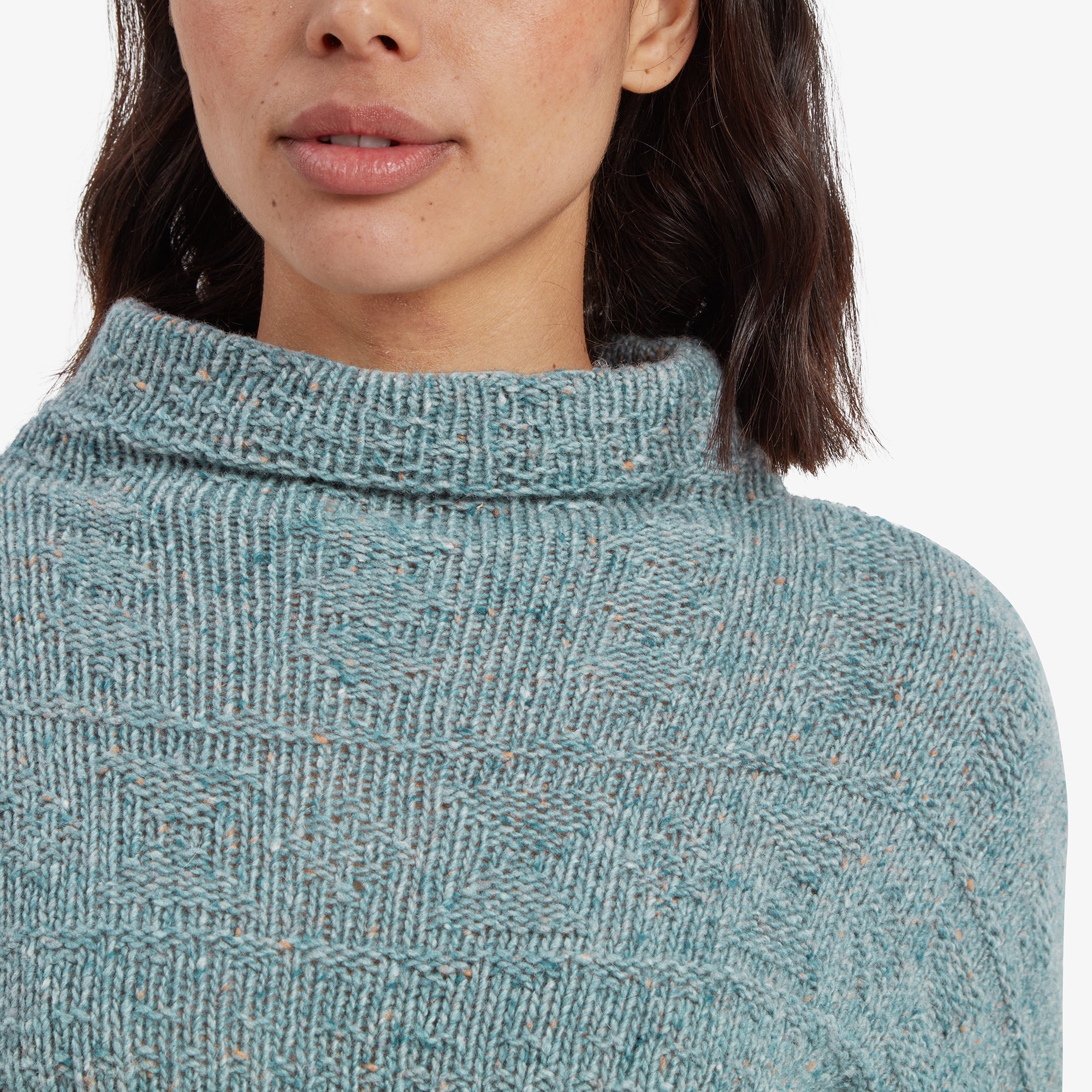 A detailed close-up focusing on the soft, textured knit of the Sherpa Adventure Gear Yuden Pullover Sweater in Green and its relaxed high neckline. The intricate weave pattern adds depth and warmth to the design.