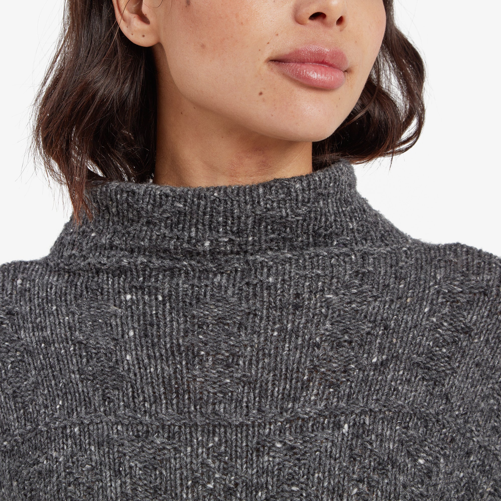 A close-up of the high neckline of the Sherpa Adventure Gear Yuden Pullover Sweater in Grey, showcasing the intricate textured knit pattern and white speckled details. The soft and thick material is evident in the image.