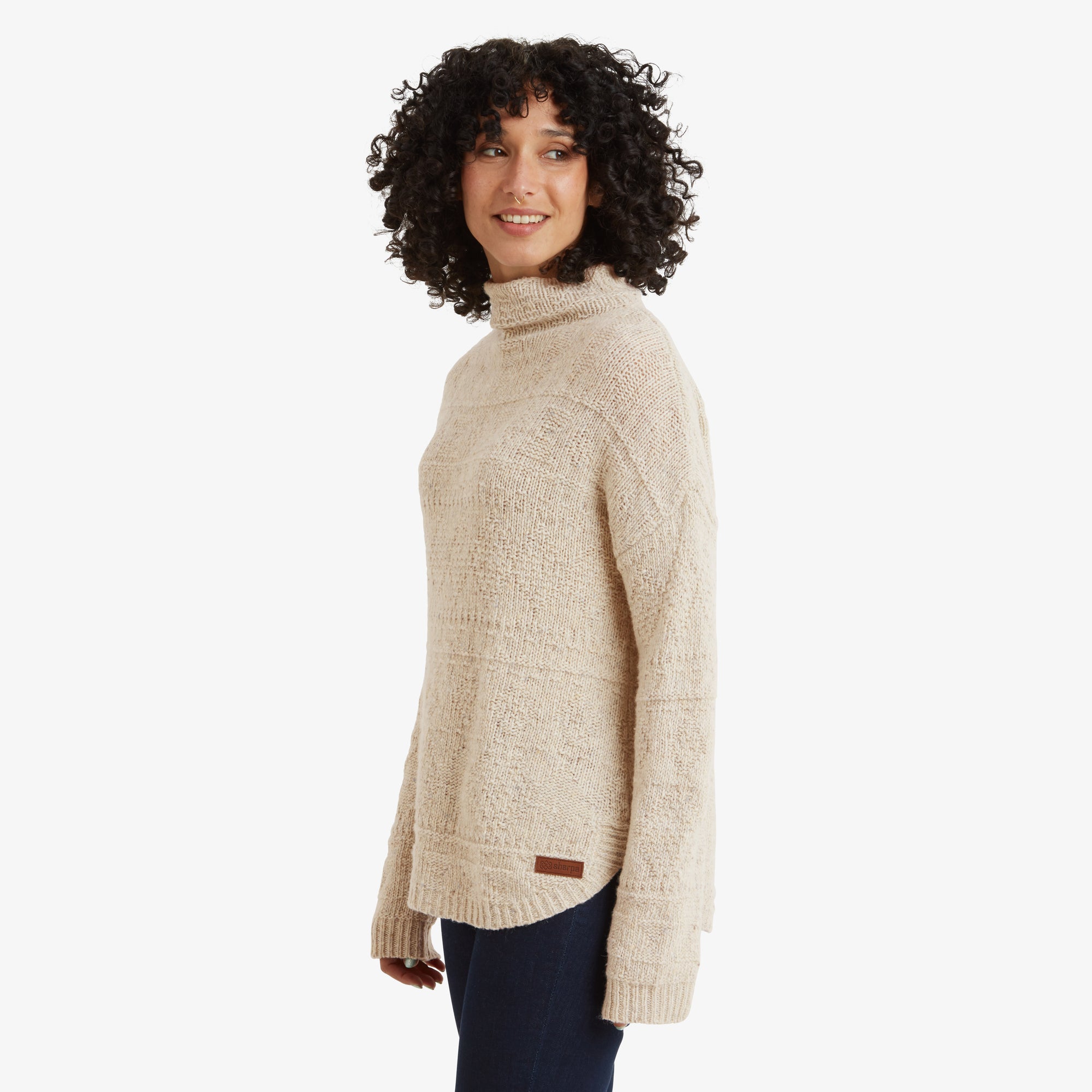 A side-view of the Sherpa Adventure Gear Yuden Sweater in White, emphasising the high neckline, long sleeves, and the soft textured knit material. The hem features a slight curve that adds a stylish detail to the relaxed silhouette.